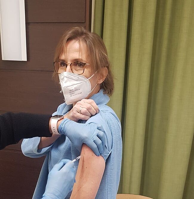 Das Foto zeigt Lehrerin Britta Meyer. Sie fixiert mit einer Hand Ihre Bluse, um sich in den Oberanrm impfen zu lassen.
