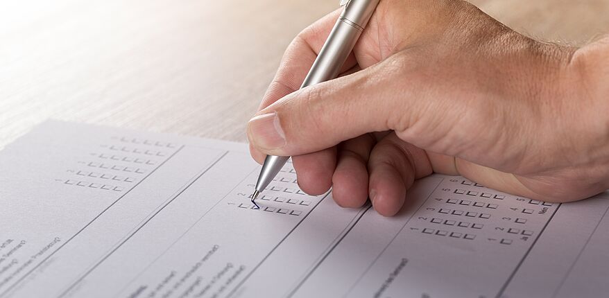 Das Foto (Symbolbild / Pixabay-Andreas Breitling) zeigt eine schreibende Hand auf einem Fragebogen
