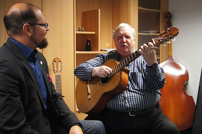Das Foto zeift Musikschulleiter Armin Hartwig mit der Gitarre in den Händen. Daneben Landrat Martin Stichnoth. 