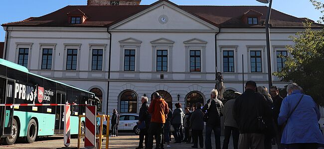 Das Foto zeigt einen Impfbus auf dem Rathausmarkt in Haldensleben. Etwa 30 Personen warten vor dem Bus auf Ihre Impfung. Im Hintergrund sieht man das Rathaus. 