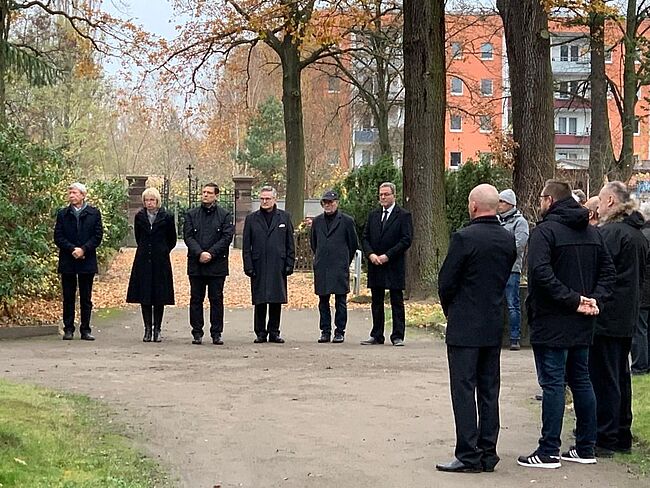 Das Foto zeigt die Teilnehmer der Veranstaltung der Stadt Haldensleben auf dem städtischen Friedhof zum Volkstrauertag. Landrat Martin Stichnoth wird von Dr. Marcus Waselewski vertreten. 